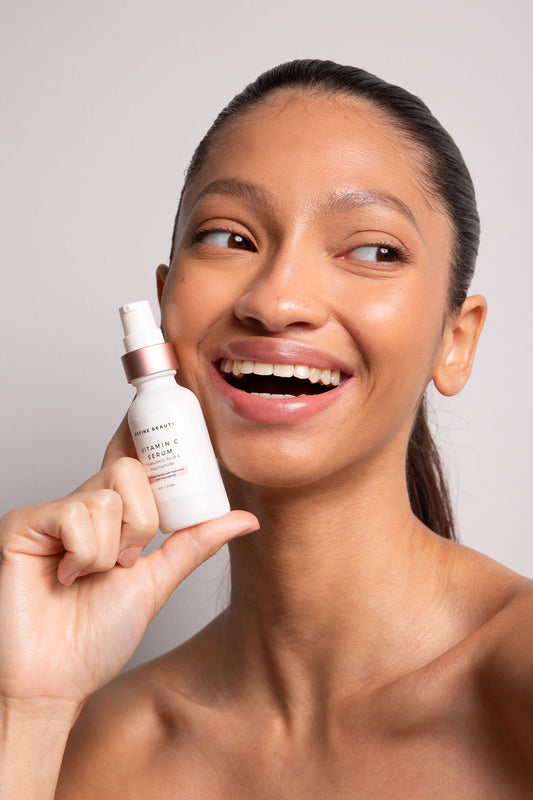 Model holding a Vitamin C Serum with Hyaluronic Acid + Niacinamide on white background 