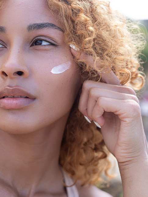 Model with aloe & avocado moisturizer smear on her cheek